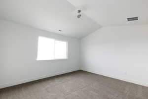Carpeted empty room with lofted ceiling and baseboards