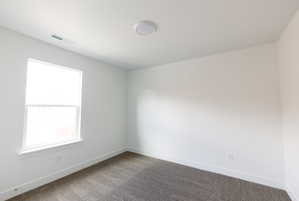 Carpeted spare room featuring baseboards