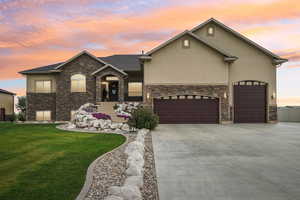 View of front of house with stone siding, a front yard, and stucco siding