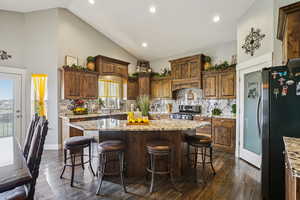 Kitchen featuring light stone countertops, decorative backsplash, high vaulted ceiling, and recessed lighting