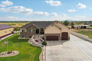 View of front of house featuring driveway, stone siding, and stucco siding