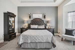 Bedroom featuring light colored carpet and a tray ceiling