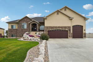 View of front of house featuring a front yard, stucco siding, and stone siding