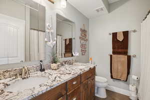 Bathroom with double vanity, dark tile patterned flooring, and a shower with curtain