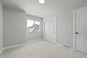 Unfurnished bedroom featuring light carpet, a textured ceiling, and a closet