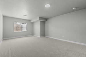 Carpeted spare room with a textured ceiling and baseboards