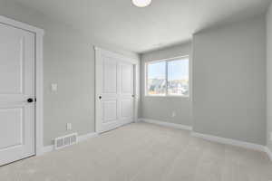 Unfurnished bedroom featuring light carpet and a closet