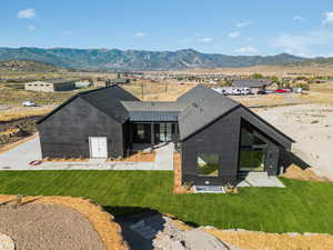 Back of property with a mountain view, a standing seam roof, a metal roof, and a lawn
