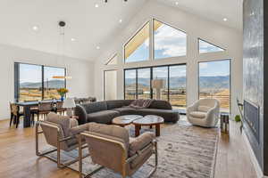 Living room with a mountain view, high vaulted ceiling, recessed lighting, light wood-style floors, and a fireplace