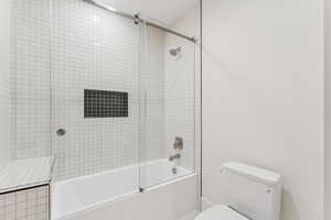 Bathroom with combined bath / shower with glass door and toilet