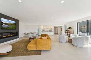 Living area featuring recessed lighting, a glass covered fireplace, and speckle patterned floor