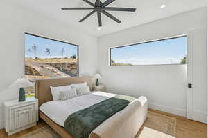 Bedroom with light wood-style floors, multiple windows, ceiling fan, and recessed lighting