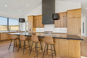 Kitchen featuring light wood-style flooring, a kitchen breakfast bar, light brown cabinets, recessed lighting, and a large island