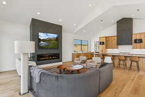 Living area featuring high vaulted ceiling, recessed lighting, light wood finished floors, and a large fireplace