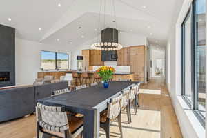 Dining space featuring light wood-style flooring, high vaulted ceiling, recessed lighting, and a large fireplace