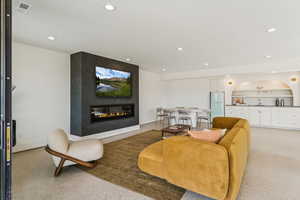 Living room featuring dark speckled floor, recessed lighting, and a glass covered fireplace