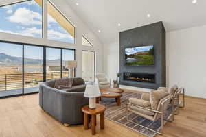 Living room with high vaulted ceiling, recessed lighting, light wood-style flooring, and a fireplace