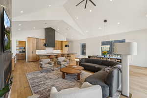 Living area featuring light wood-style flooring, high vaulted ceiling, and recessed lighting