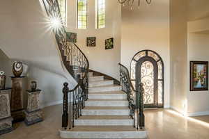 Foyer entrance featuring arched walkways, a high ceiling, stairs, a chandelier, and light tile patterned floors