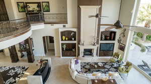 Living room with a towering ceiling, a fireplace, arched walkways, and ceiling fan