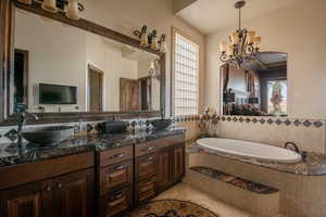 Full bath featuring double vanity, plenty of natural light, a bath, and light tile patterned flooring