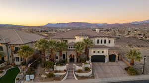Mediterranean / spanish house with stucco siding, driveway, stone siding, an attached garage, and a mountain view