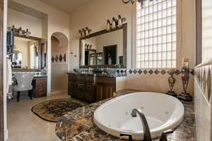 Full bathroom with vanity, a tub with jets, and light tile patterned flooring