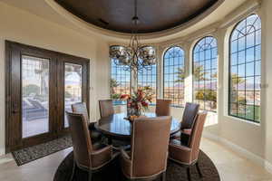 Dining room with a raised ceiling, light tile patterned floors, and a chandelier
