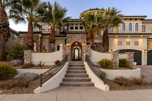 Mediterranean / spanish-style house with stone siding, stucco siding, an attached garage, and a fenced front yard