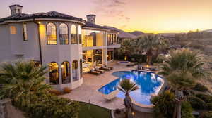Back of property featuring an outdoor pool, a patio area, a balcony, stucco siding, and an in-ground hot tub
