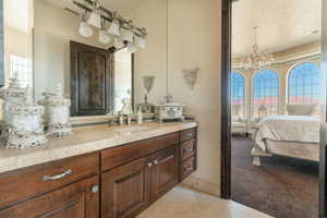 Ensuite bathroom with vanity, a chandelier, and light tile patterned floors