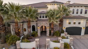 Mediterranean / spanish house with stucco siding, driveway, stone siding, a garage, and a tile roof