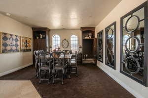 Dining area featuring dark colored carpet, a textured ceiling, and dark tile patterned flooring