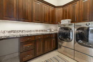 Washroom with independent washer and dryer, cabinet space, and light tile patterned floors