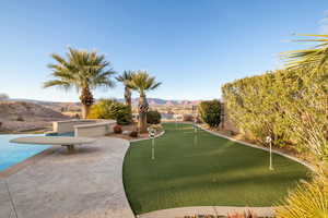 View of community featuring a putting green, a mountain view, and a patio