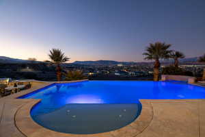Pool at dusk with a mountain view, a patio area, and a pool with connected hot tub