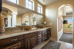 Bathroom featuring vanity, a ceiling fan, decorative backsplash, a high ceiling, and light tile patterned floors