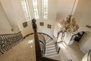 Stairs with a high ceiling, a chandelier, arched walkways, and tile patterned floors
