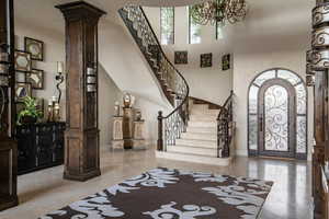 Entrance foyer with ornate columns, healthy amount of natural light, stairs, a towering ceiling, and a chandelier