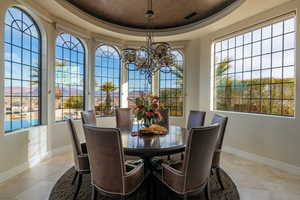 Dining room with a raised ceiling, light tile patterned floors, and a chandelier