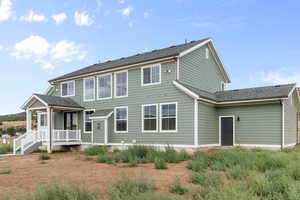 Back of house featuring a shingled roof and a porch