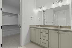 Full bath featuring double vanity, a spacious closet, and light tile patterned flooring