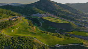 Aerial view of property's location featuring a golf course and a water and mountain view