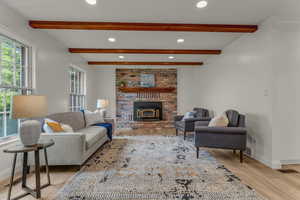Living room with recessed lighting, beamed ceiling, light wood finished floors, and a brick fireplace