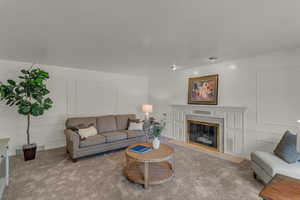Carpeted living area featuring a decorative wall and a high end fireplace