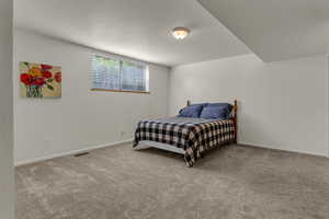 Carpeted bedroom featuring baseboards and a textured ceiling