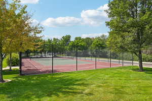 View of tennis court featuring view of wooded area