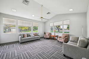 Carpeted living area featuring lofted ceiling and ceiling fan