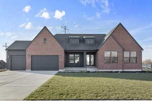View of front of property with covered porch, driveway, a garage, roof with shingles, and brick siding