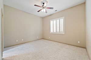 Carpeted guest room with a ceiling fan and baseboards